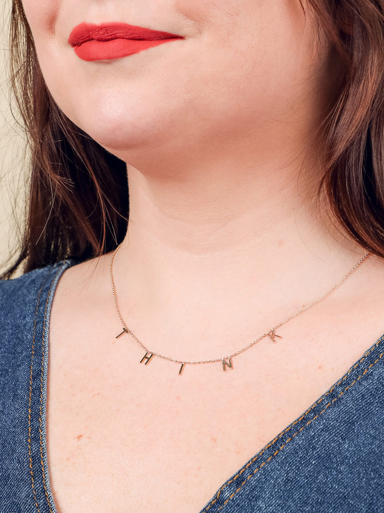 "Think" message necklace on smiling model in yellow gold