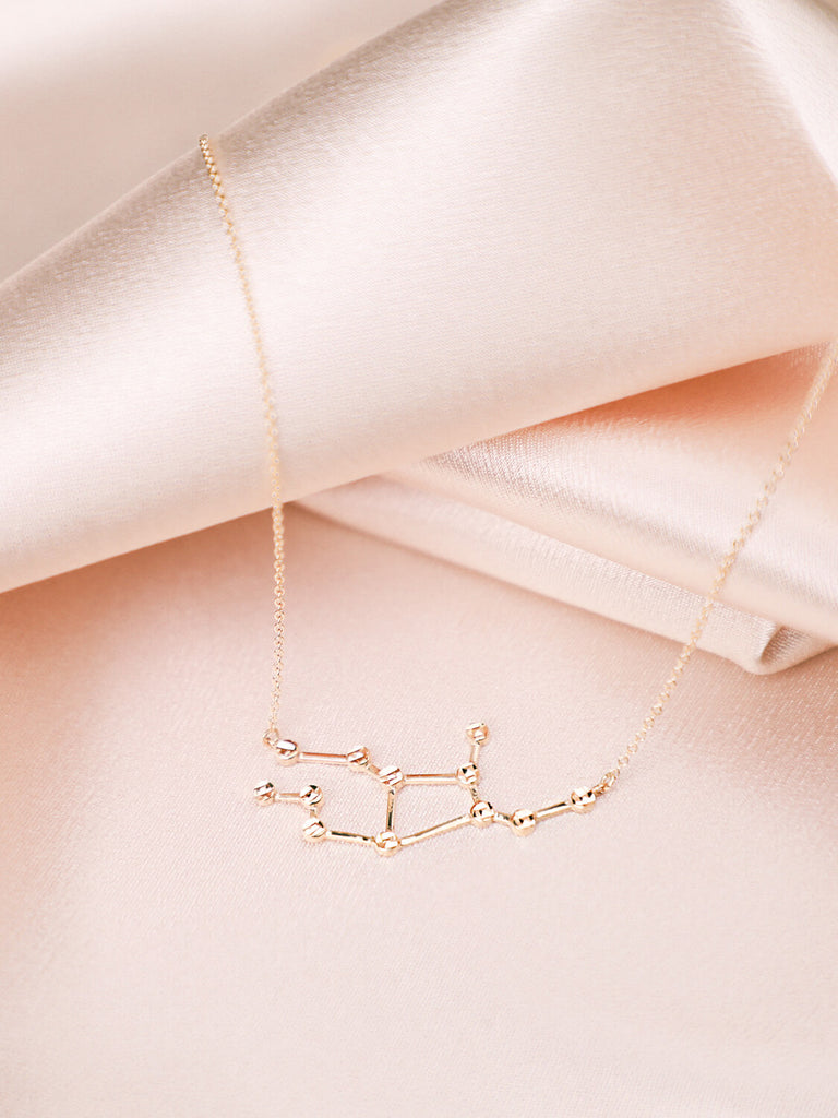 gold virgo constellation necklace on satin background