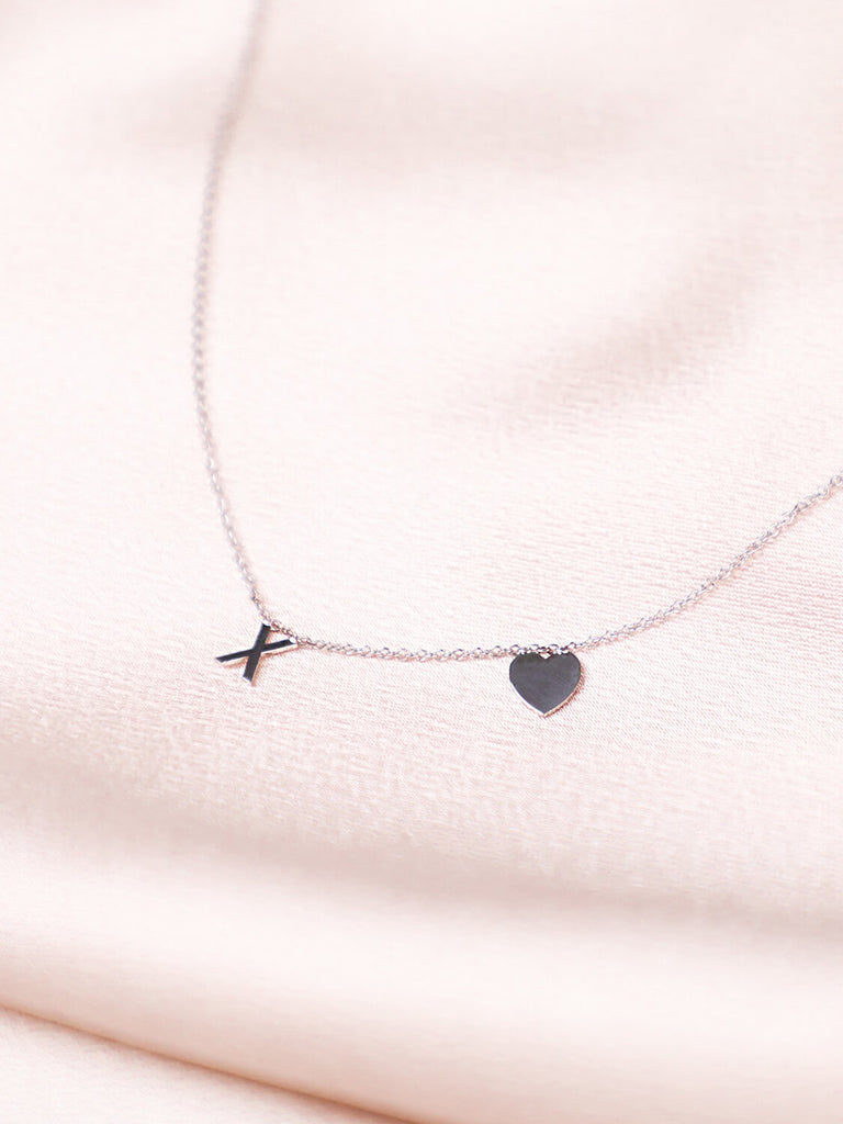 closeup of 14k White gold XO Love Never Dies necklace against pink satin