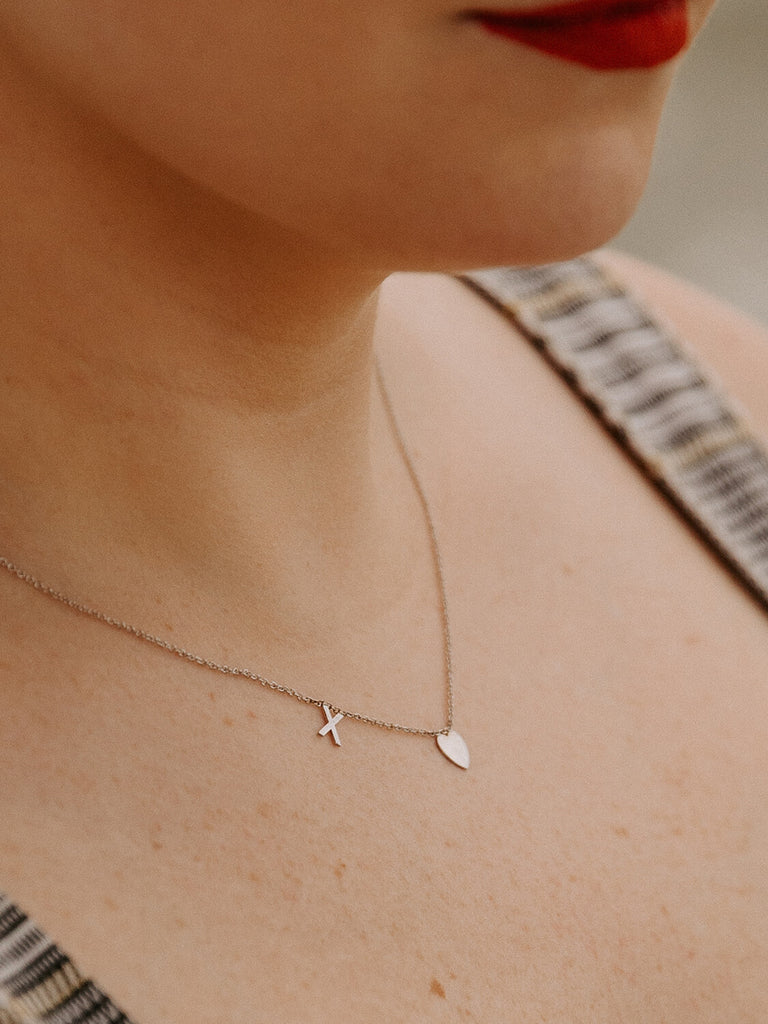 Female model wearing X and Heart necklace in white gold